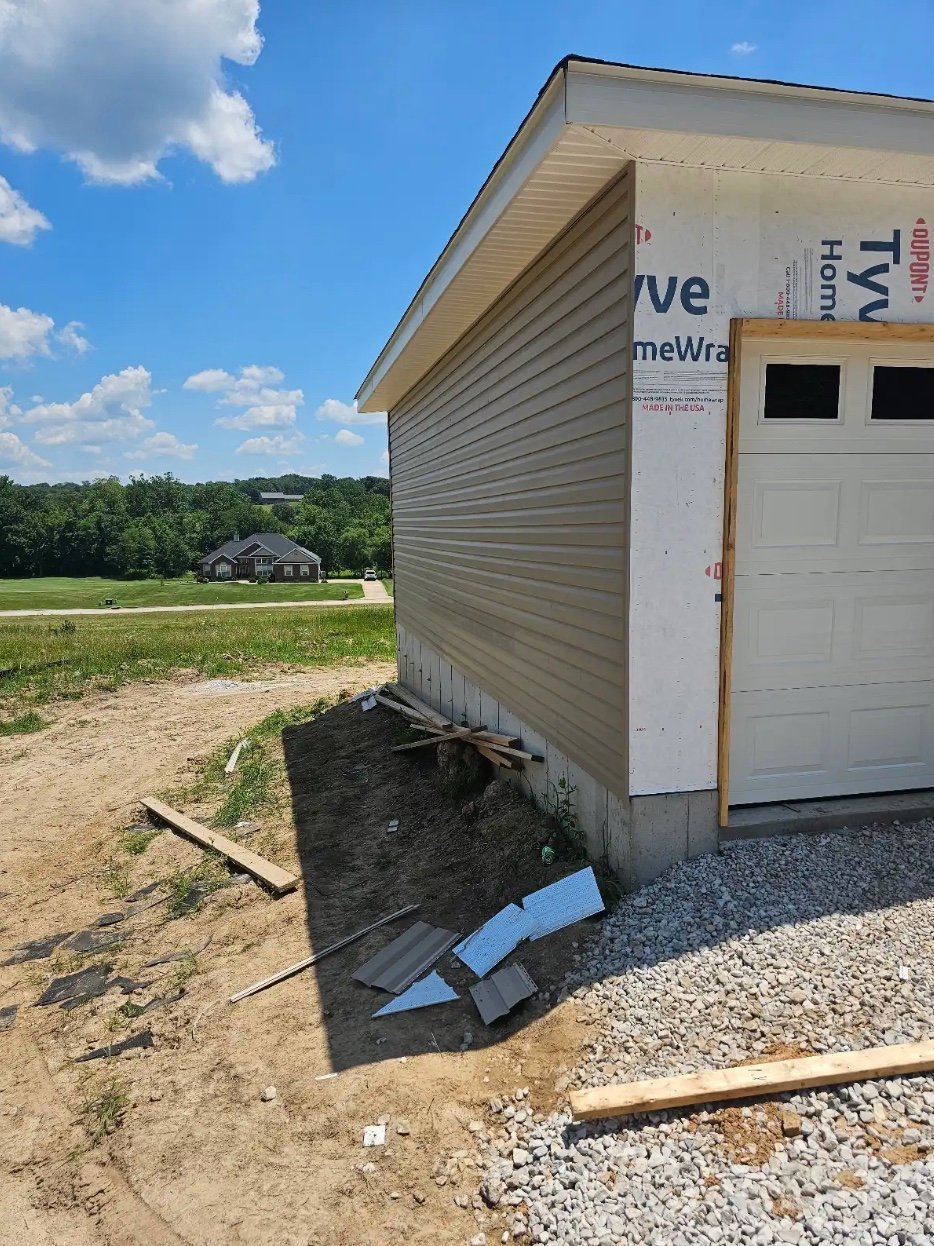 New construction home with white garage door and tan siding
